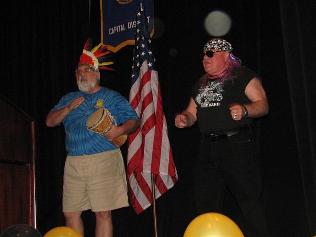 IMG_6512.JPG - OK, now you know.  Not all Kiwanians can do “YMCA”!   The new “Capital Kiwanis Players” made an appearance to sing and dance, no less, with walker & crutches no less, to the YMCA song.  You really had to see it. Photos give you a touch, but just a touch.  Indian Joe beats his drum to the beat, sort of, while GE Tom just jumped off his bike.