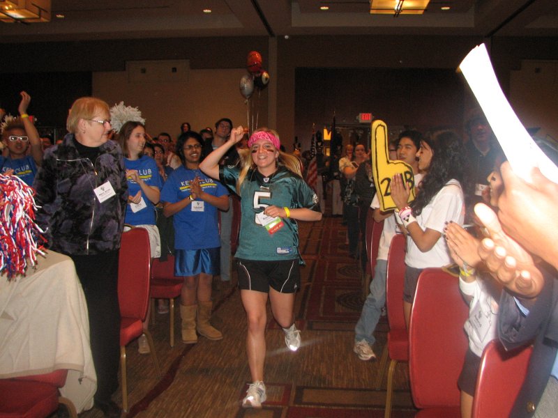 IMG_0680.JPG - Capital District Key Club Governor Rachael Slotter, Stephen Decatur High School, races into the ballroom to cheers in her field hockey ‘Just Serve It’ uniform.  She races on stage … brings the Lieutenant Governors on stage and gavels the session to order.